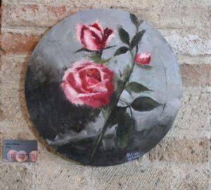 An oil painting of a pink flower on a circular canvas